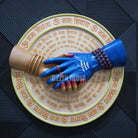 Decorative plate with hands and text on a textured surface